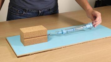 A wooden block is dragged across a surface using a spring scale, demonstrating friction and force measurement video