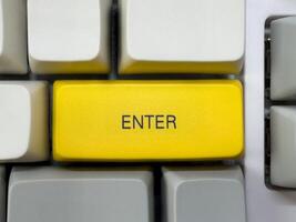 Big yellow Enter button with text on mechanical white keyboard, business concept, for advertising photo
