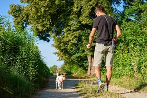 Man walking with small dog on countryside path in summer photo
