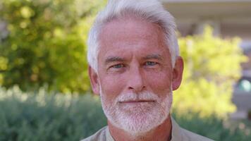 Closeup portrait of confident senior businessman smiling in park video