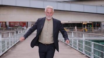 Smiling senior businessman dancing joyfully on pedestrian bridge video