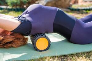 Woman lying on a mat with a foam roller under her upper back during spine mobility practice. Posture correction, back release, and body alignment routine. High quality photo