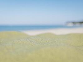 Sandy beach close-up with the blurred blue ocean and cloudy sky. photo