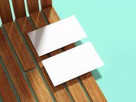 Two white business cards placed on a wooden surface with soft shadow play. photo