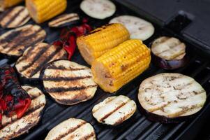 Grilled vegetables on barbecue including corn, eggplant, and bell peppers photo