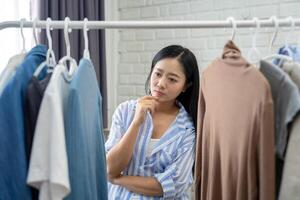 Beautiful Asian girl standing deciding on clothes to go out tomorrow photo