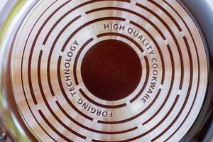 Close up of the bottom surface of a high quality non stick frying pan with engraved text and concentric metal rings. Concept for modern kitchenware, durable cookware, and cooking technology photo