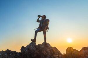 man is standing on a mountain top, looking through a camera lens photo