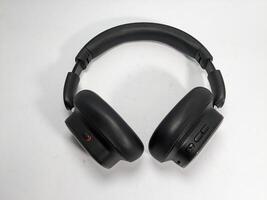 Overhead shot of modern black wireless headphones on a white surface background photo