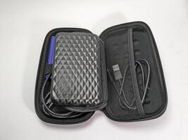 Open Black Case with External Hard Drive, Cable, and Accessories on White Surface photo