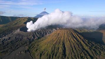 Aerial view of active Mount Bromo volcano emitting smoke with erupting Mount Semeru in the background. Stunning volcanic landscape in East Java, Indonesia. Raw nature, power, and geological beauty. video