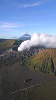 Aerial view of active Mount Bromo volcano emitting smoke with erupting Mount Semeru in the background. Stunning volcanic landscape in East Java, Indonesia. Raw nature, power, and geological beauty. video