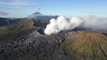 Aerial view of active Mount Bromo volcano emitting smoke with erupting Mount Semeru in the background. Stunning volcanic landscape in East Java, Indonesia. Raw nature, power, and geological beauty. video