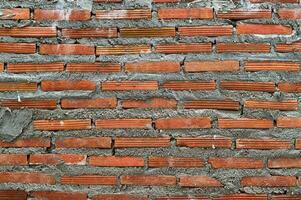 Red brick wall background texture with rough cement masonry. closeup view of house during construction or renovation project showing an old and weathered surface photo