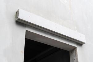 White architectural lintel installation over window opening on concrete wall. Close up detail of building site during thoughtful house renovation and construction photo