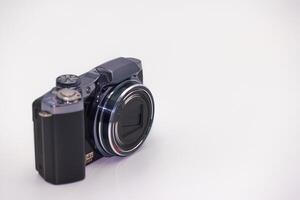 Compact digital camera positioned on a white surface showcasing modern design with clear lens and creative potential photo