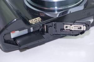 Camera showcasing a 24x wide zoom lens with an open compartment for battery and memory card access photo