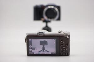 Camera setup on a tripod with a digital display showing reflection of another camera behind it photo