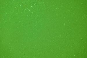 Bright green sparkling surface with tiny glitter particles shining under light photo