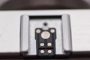 Close up view of a metal component with electrical contacts on a smooth surface in a workshop setting photo