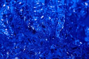 Abstract blue foil texture with shiny and crinkled surface capturing light in unique patterns photo