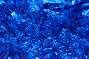 Bright blue crumpled aluminum foil creating an abstract textured background with a shiny surface reflecting light photo