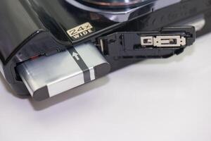 Close up view of a digital camera battery compartment showing battery insertion process photo