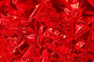Bright red crinkled foil texture for creative design and artistic projects in various applications photo