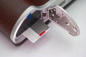 Close up view of a camera revealing the memory card compartment with a silver and red memory card inserted photo