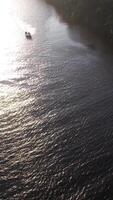 Aerial view of a speedboat navigating a river, surrounded by lush greenery, under bright sunlight video