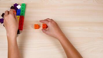 Hands assembling colorful linking cubes on table video
