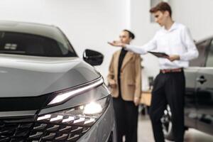 A car dealer advises a customer on the purchase or lease of a new car. The concept of an expensive purchase or lease of a modern car. photo