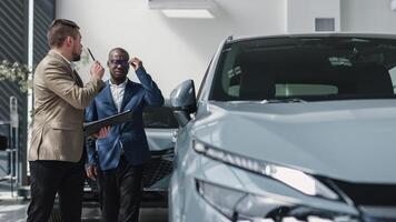 Dealer helps customer choose new car in showroom. Concept of buying, leasing, test drive and renting car. photo