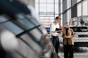 A car dealer in a modern car dealership advises a customer on buying or leasing a new car. The concept of an expensive purchase or lease of a modern car. photo