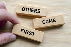 Others come first message on wood blocks, reinforcing the idea that effective leadership involves serving and uplifting others consistently photo