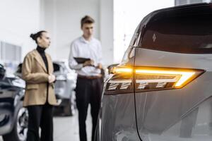 An African American dealer helps a customer choose a new car in a modern car dealership. The concept of buying, leasing, test driving and renting a car. photo
