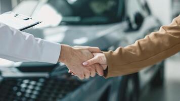 A car dealer completes a deal or a successful consultation by shaking hands with a customer. Concept of a successful purchase and sale photo