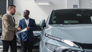 A dealer advises a client on purchasing a modern car at a car dealership. The concept of purchasing, renting and test-driving a new modern car photo