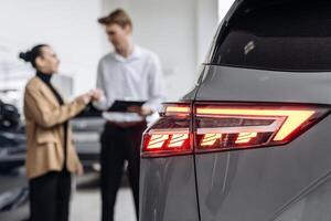 A dealer advises a client on purchasing a modern car at a car dealership. The concept of purchasing, renting and test-driving a new car photo