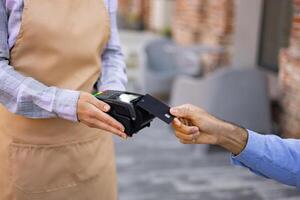 A female waiter with a cash register and a portable terminal asks to pay for the order. photo