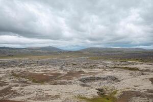 Vast lava field blanketed with soft moss stretches to the horizon on the Snafellsnes Peninsula in Iceland. The overcast sky adds a moody atmosphere to the rugged volcano photo