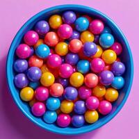 A bowl full of colorful balls on a pink background photo