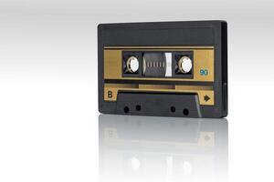Retro magnetic audio cassette with golden label reflected on glossy white surface photo