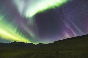 Radiant curtains of green sweep across the mountain horizon. photo