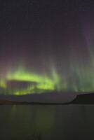 Dancing aurora borealis ribbons crown the mountain skyline. photo