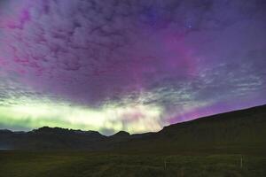 Undercurrents of aurora borealis flow above stony summits. photo