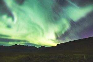 Flickering aurora streams trace the mountain outline. photo