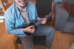 He strums a reggae rhythm on his four-string instrument photo