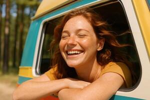 Joyful redhead woman laughing from van window in sunlit forest adventure photo