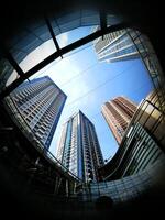Photo tall modern buildings standing against a bright blue sky, ideal for urban landscape, city architecture, business district, and travel-related themes.